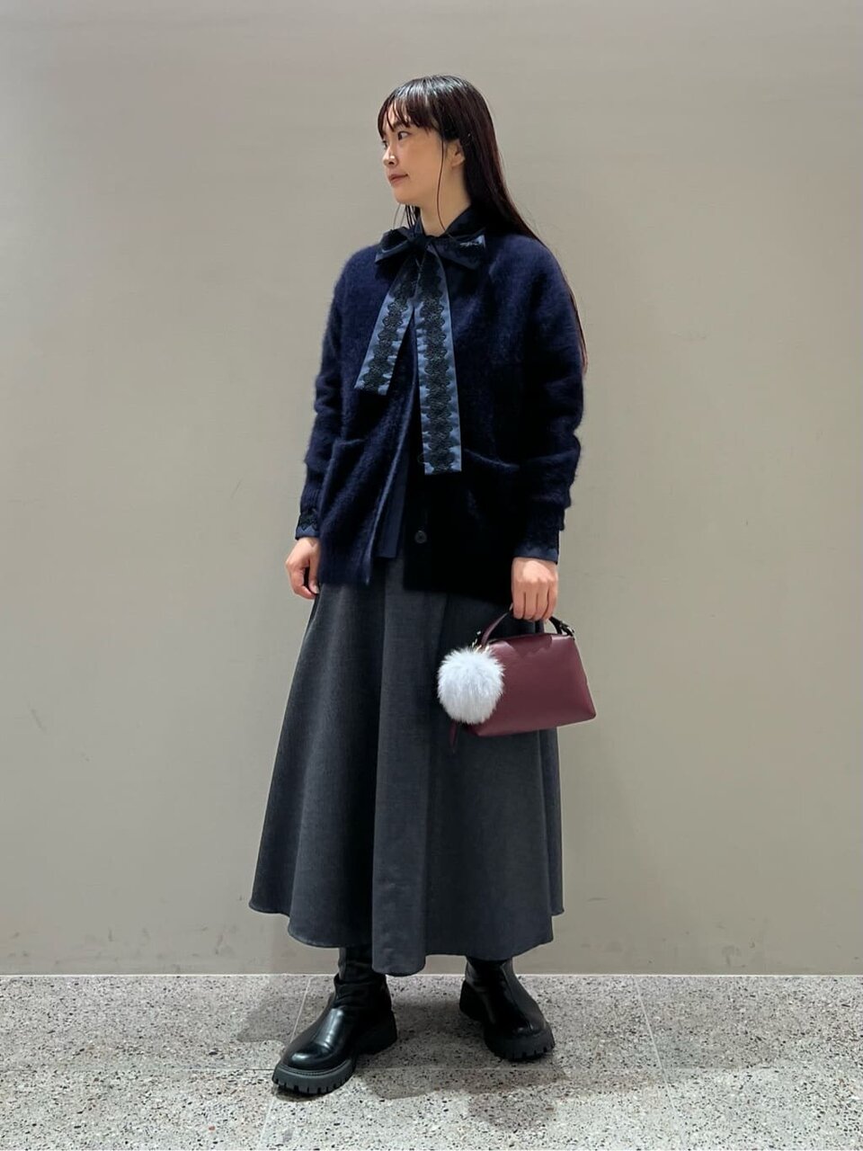 ネイビーのニットとフレアスカートを着た女性