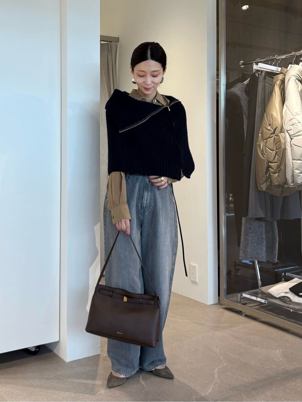 ネイビーのケープとグレーのパンツを着た女性