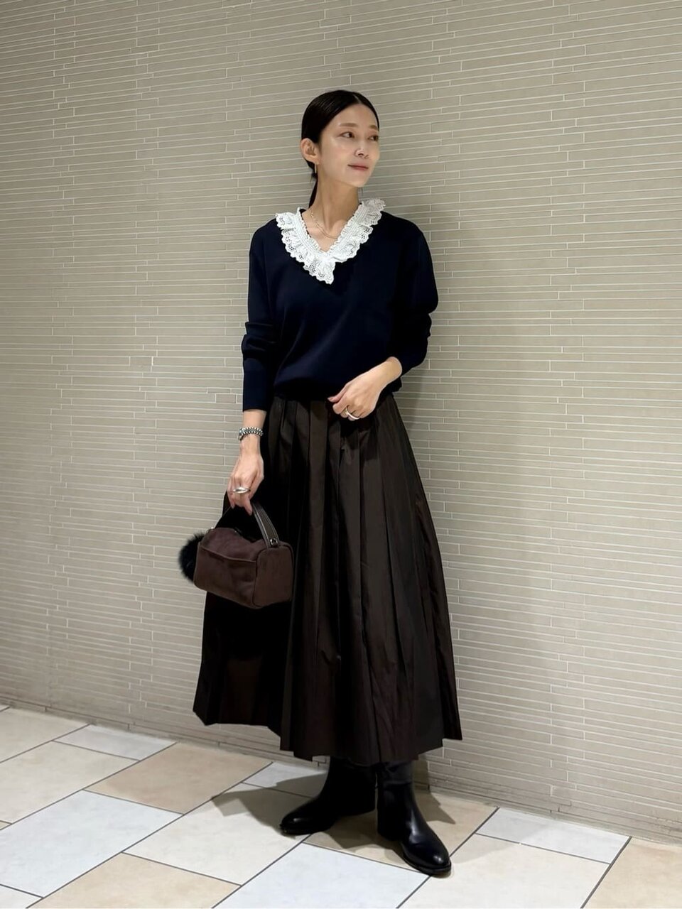 フリルつきニットとスカートを着た女性