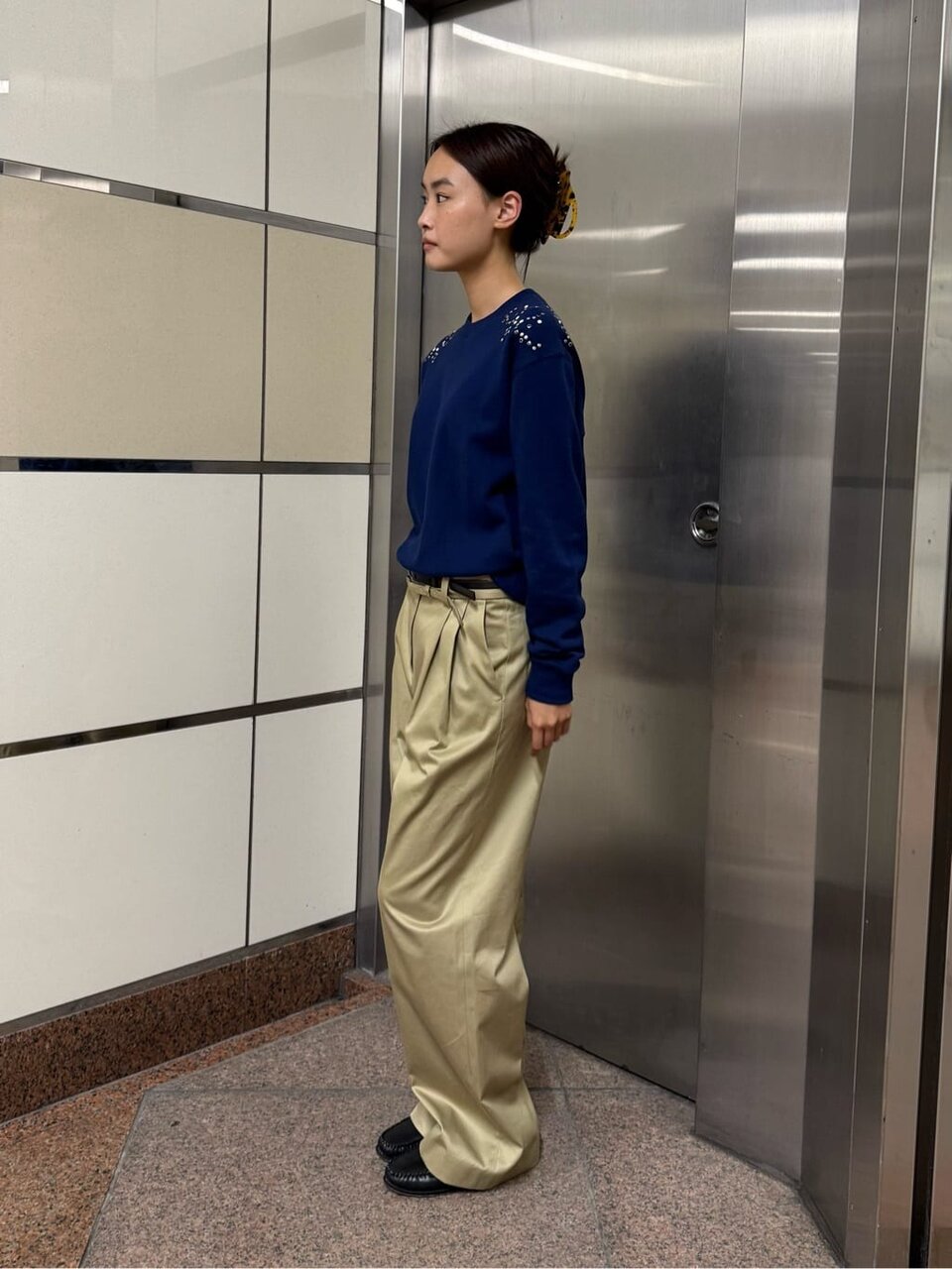 ネイビーニットとベージュのパンツを着た女性