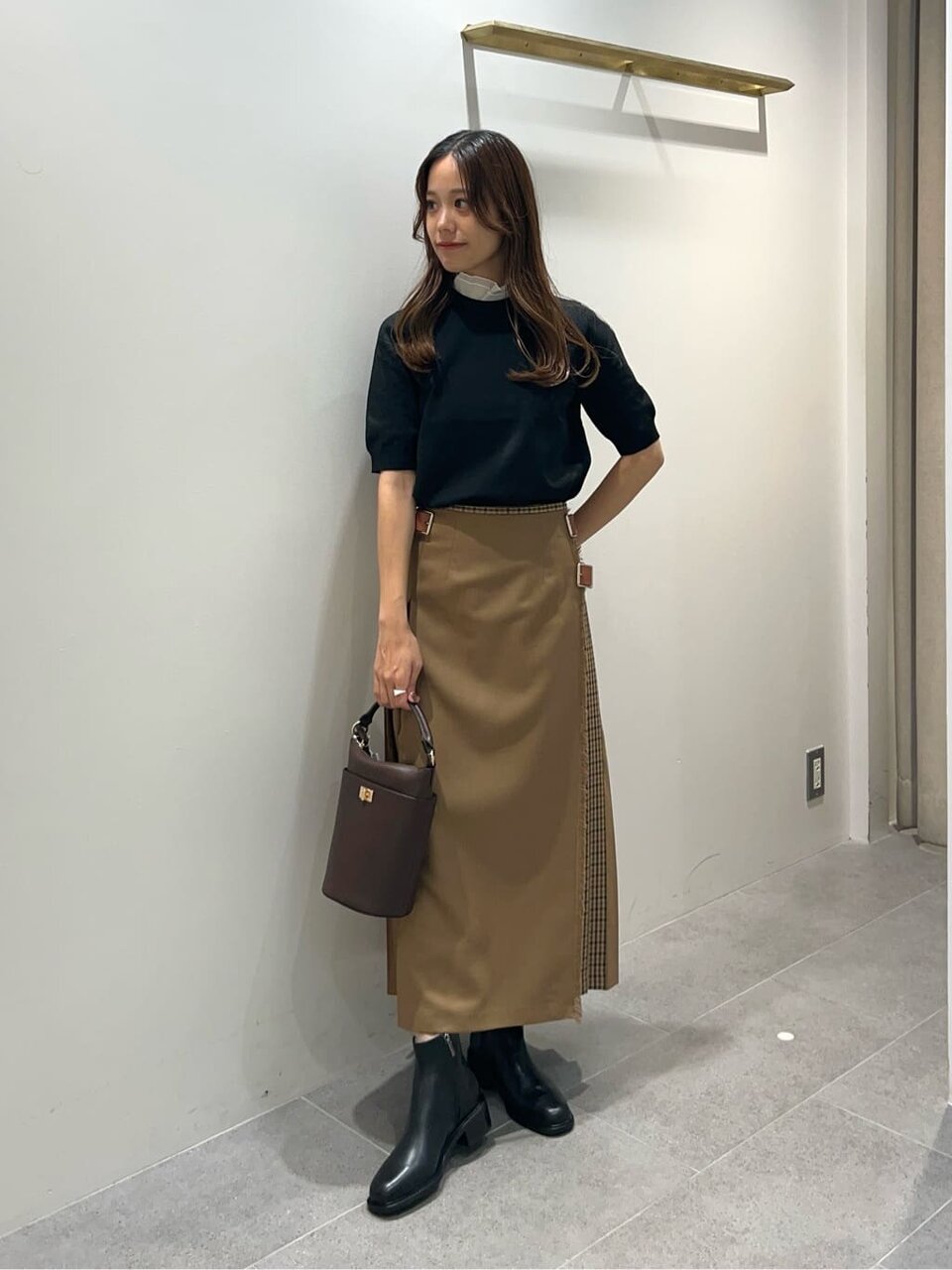 ネイビーのニットとベージュのスカートを着た女性