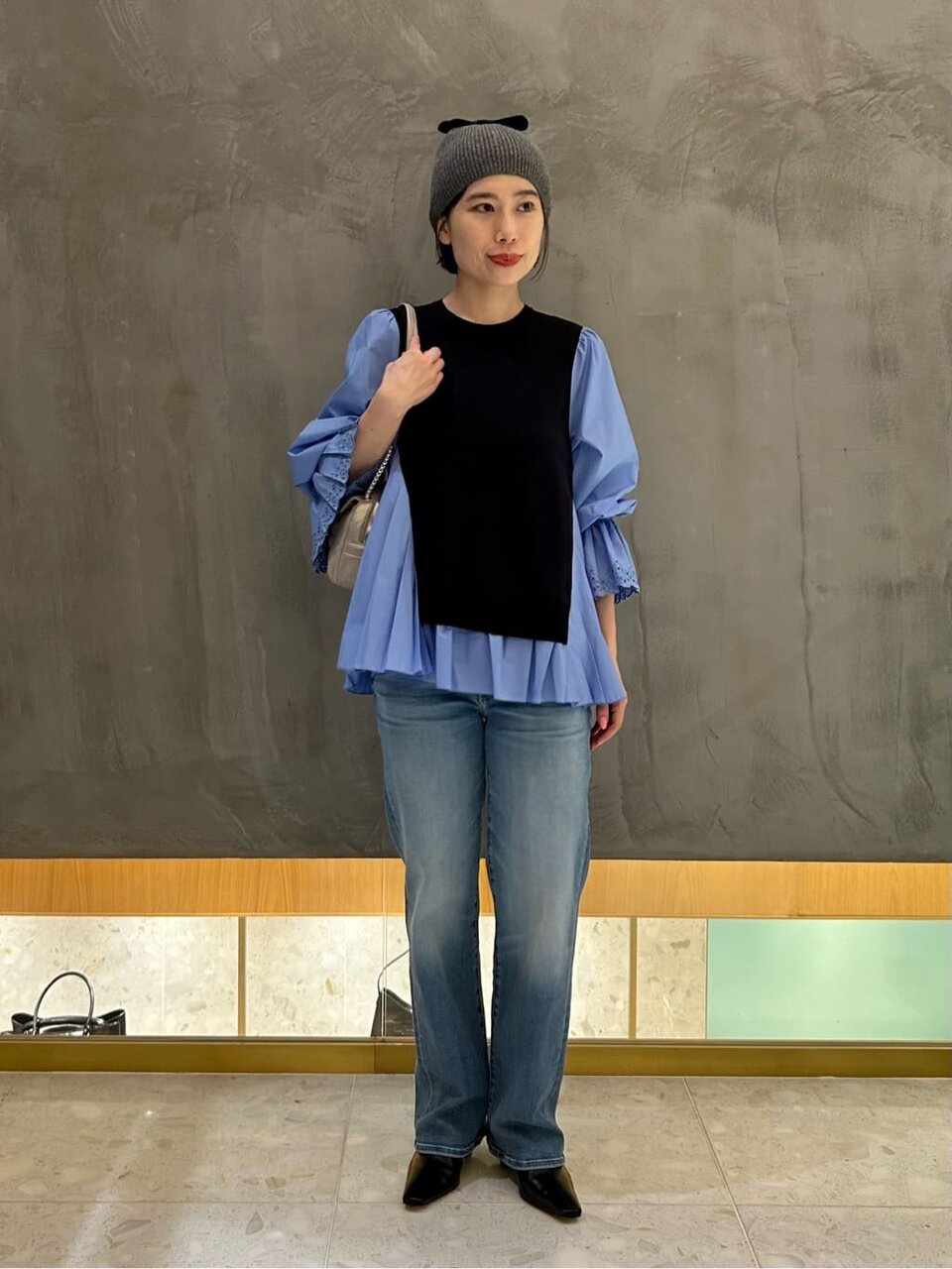 ブルーのブラウスとネイビーのベストを着た女性