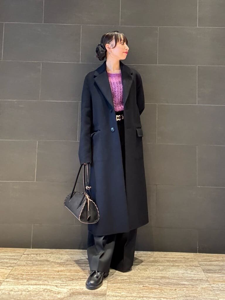 ネイビーのコートとパープルのニットを着た女性