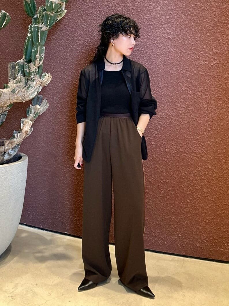 黒のシャツと茶色いパンツを着た女性