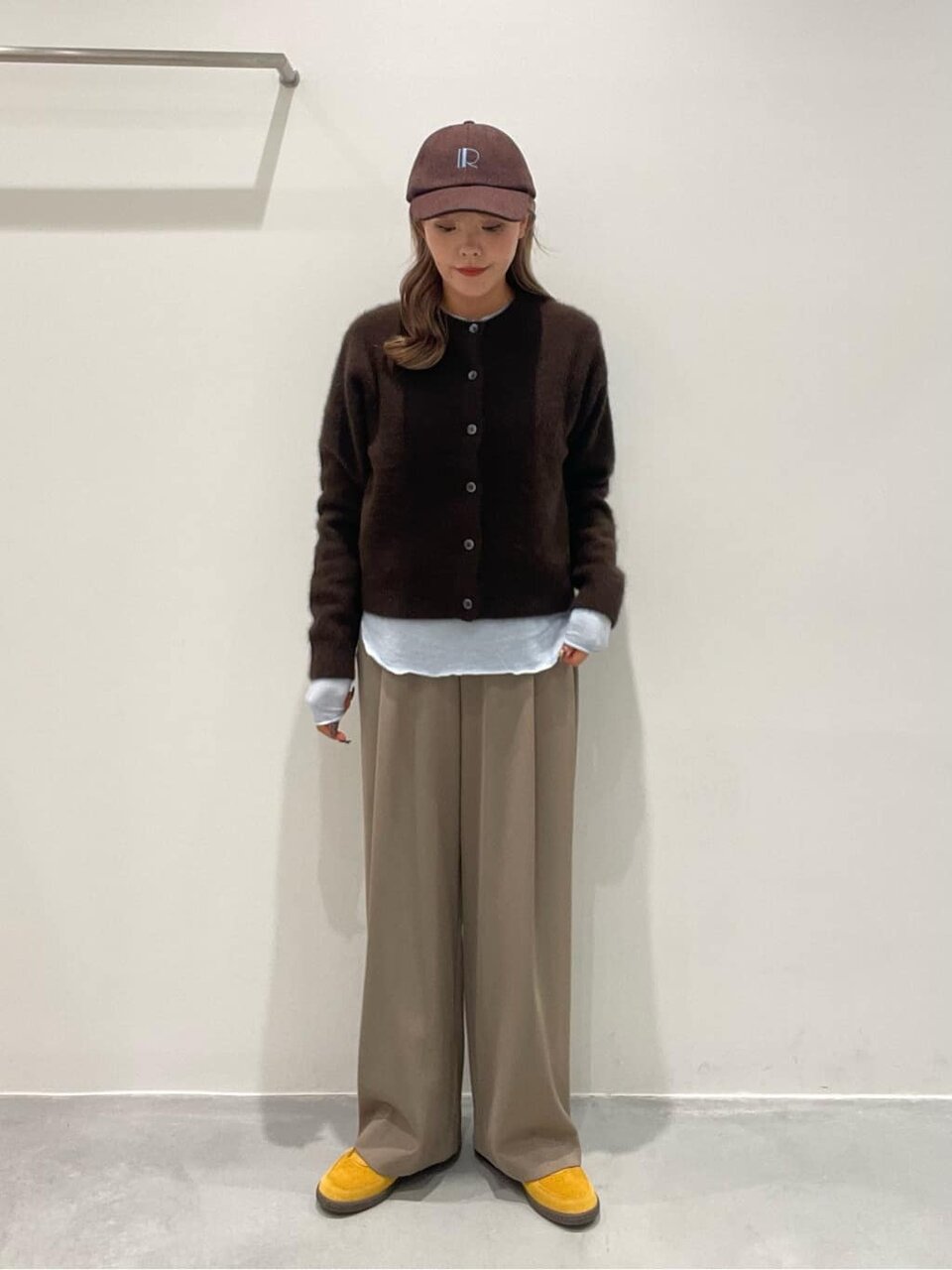 茶色いニットとベージュのパンツを着た女性