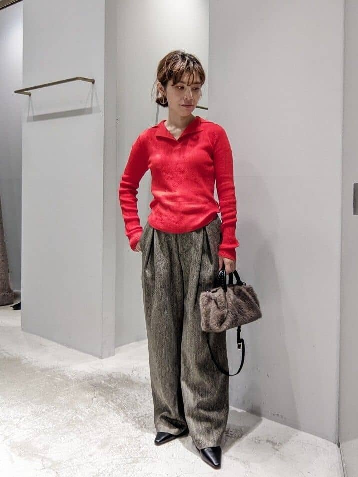 赤いニットと茶色いパンツを着た女性