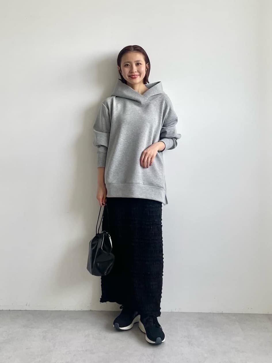 グレーのフーディーと黒のスカートを着た女性