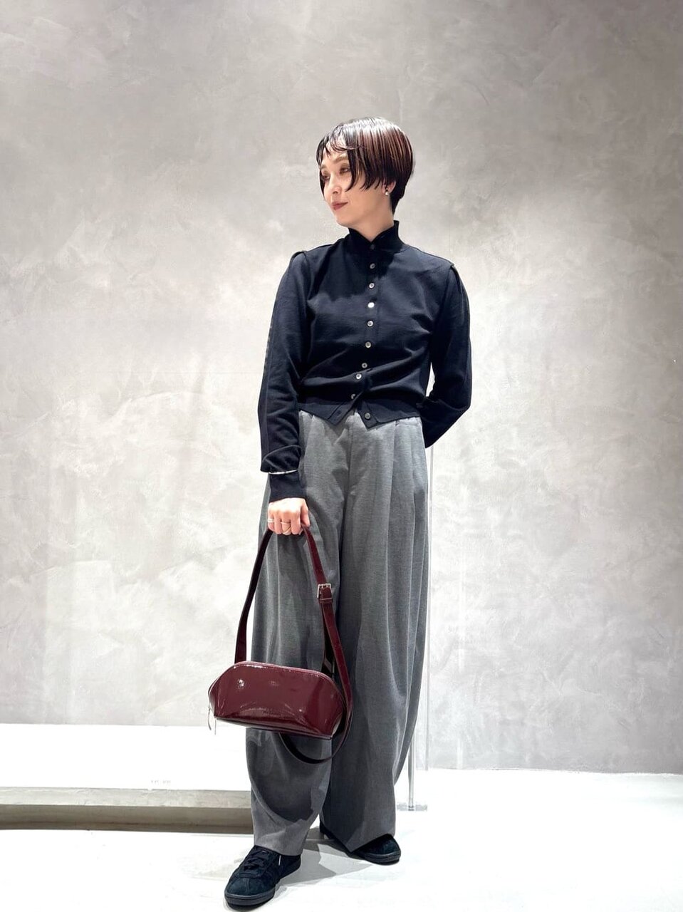 黒のカーディガンとグレーのパンツを着た女性