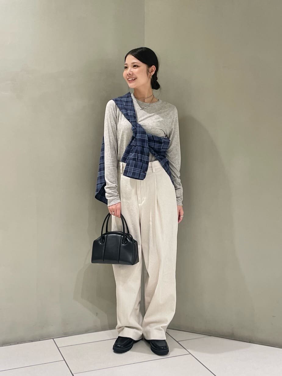 グレーのロンTと白いパンツを着た女性