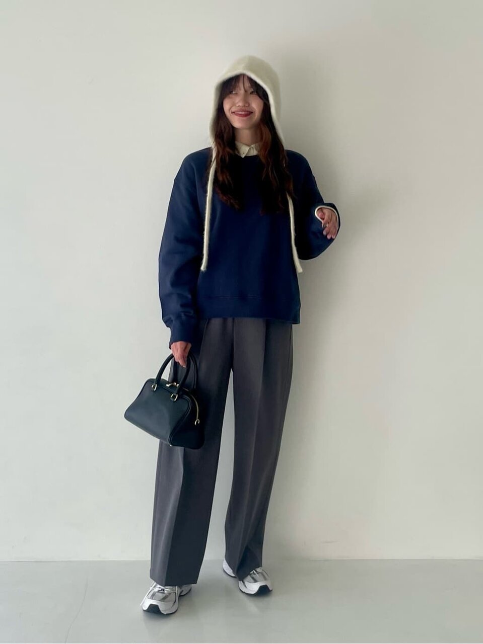 ネイビーのスウェットとグレーのスラックスを着た女性