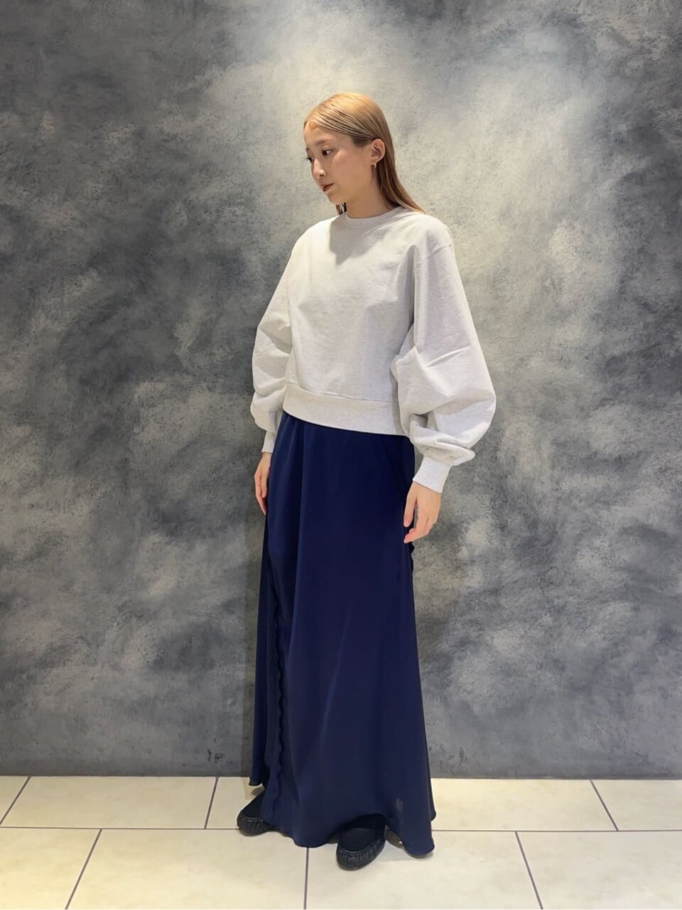 グレーのスウェットとサテンスカートを着た女性