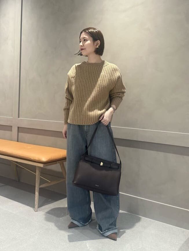 ベージュのニットとグレーのパンツを着た女性