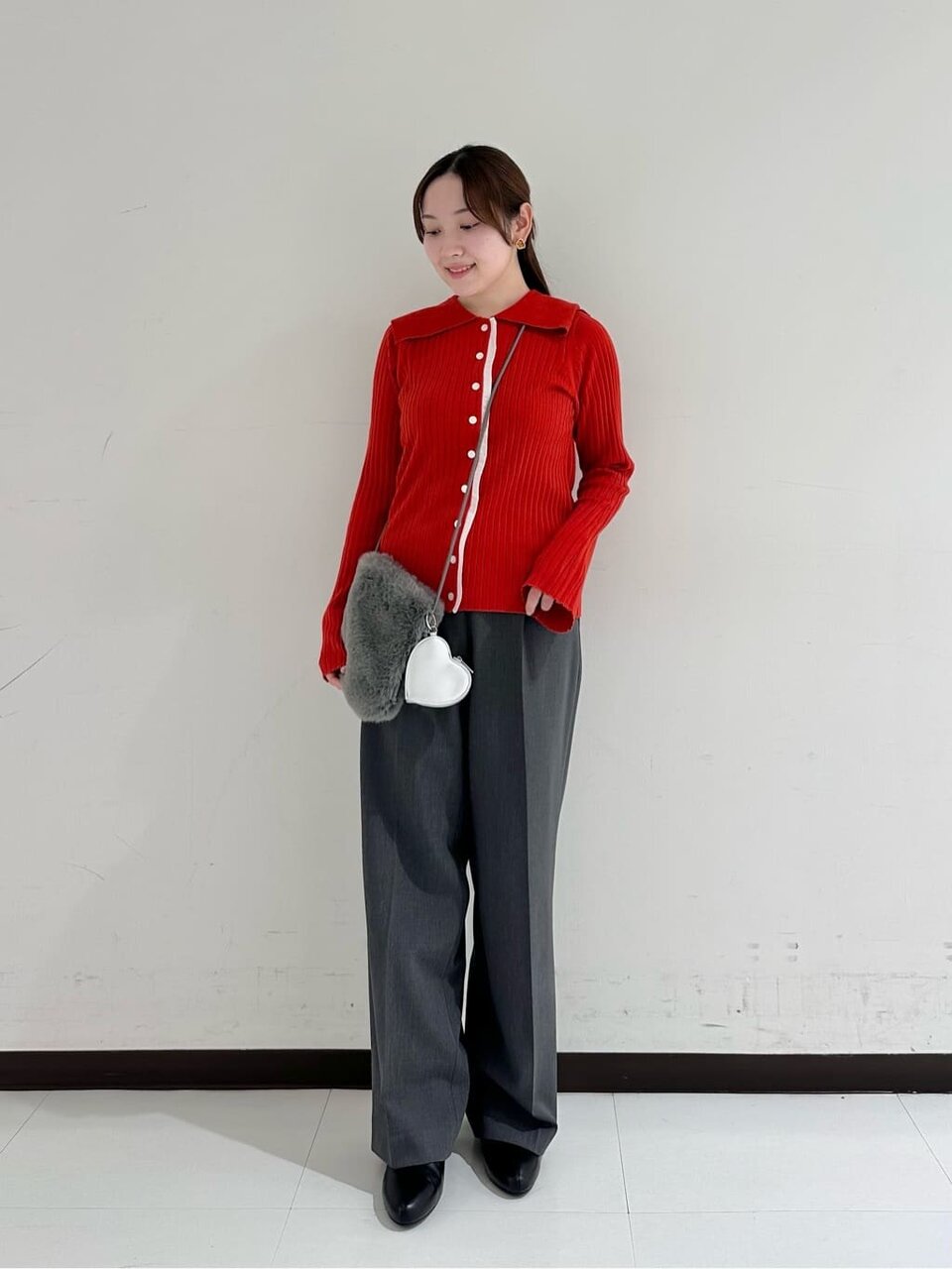 赤いニットとグレーのパンツを着た女性