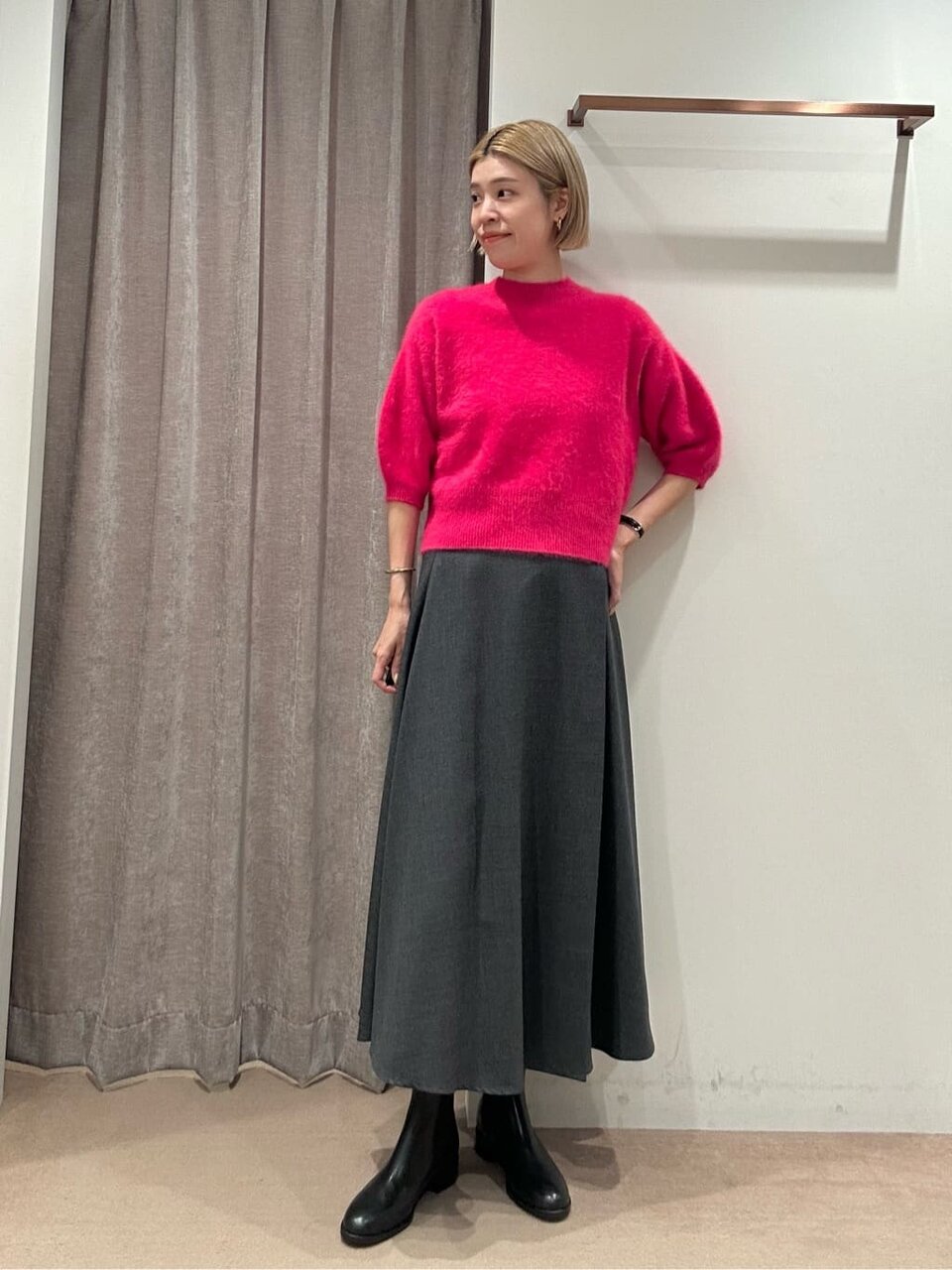 ピンクのニットとグレーのスカートを着た女性