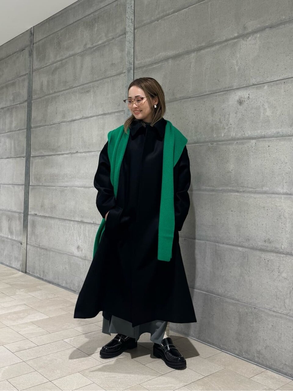 ステンカラーコートに緑のマフラーをあわせたコーデ