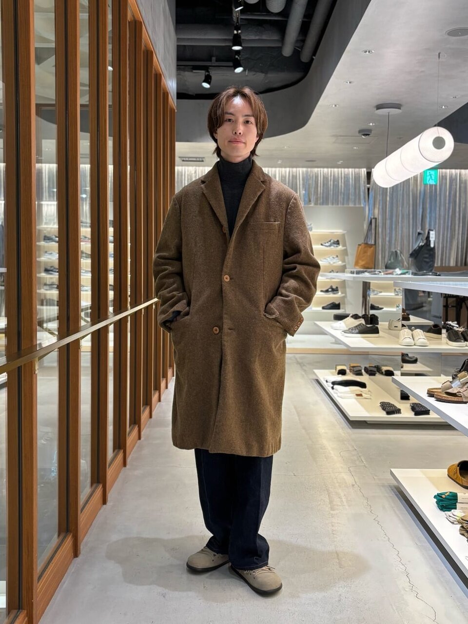 オリーブカラーのチェスターコートを着た男性