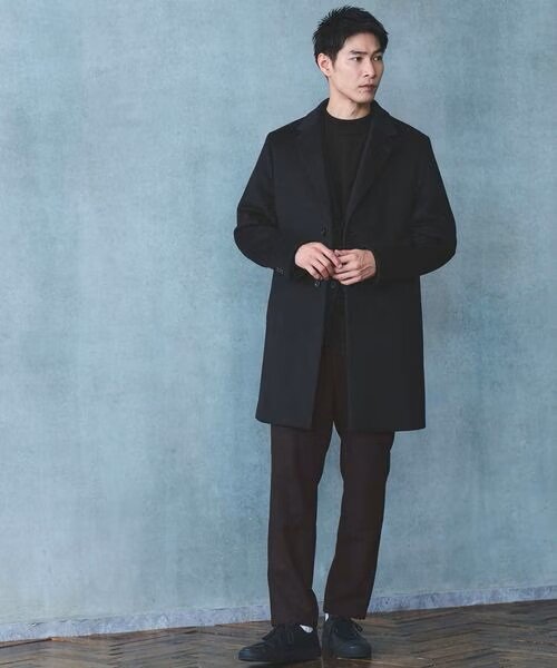 ネイビーのチェスターコートを着ている男性