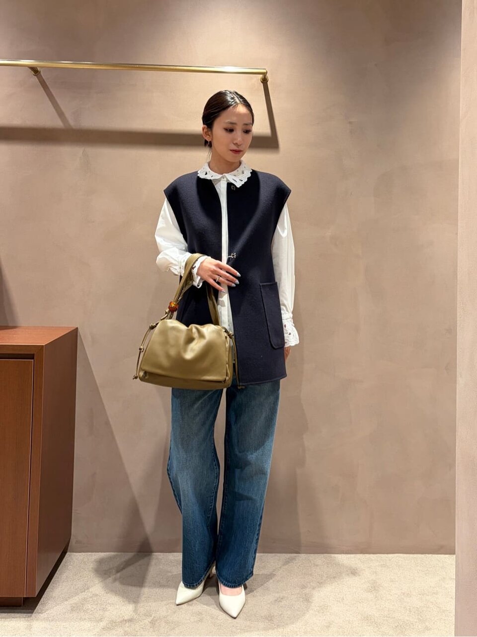 白いシャツとネイビーのベストを着た女性