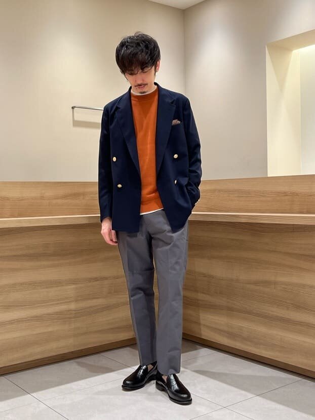 ネイビーのジャケットとオレンジのニットを着た男性