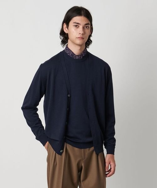 ネイビーのカーディガンとクルーネックセーターに、スカーフを巻いている人。