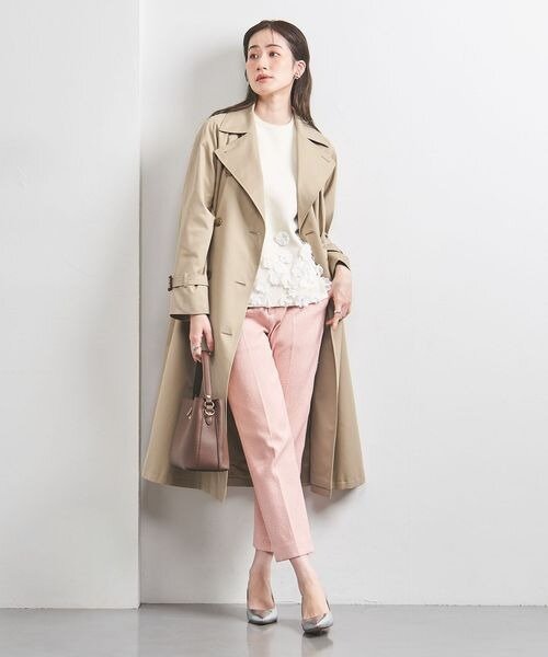 ピンクのパンツにトレンチコートをあわせた女性