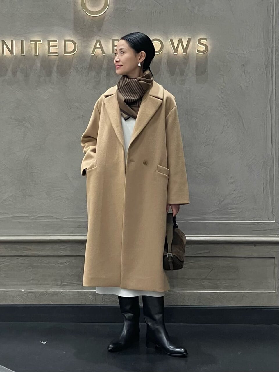 ベージュのアウターにブラウンのスカーフをあわせた女性