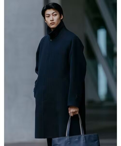 ネイビーのステンカラーコートを着ている男性