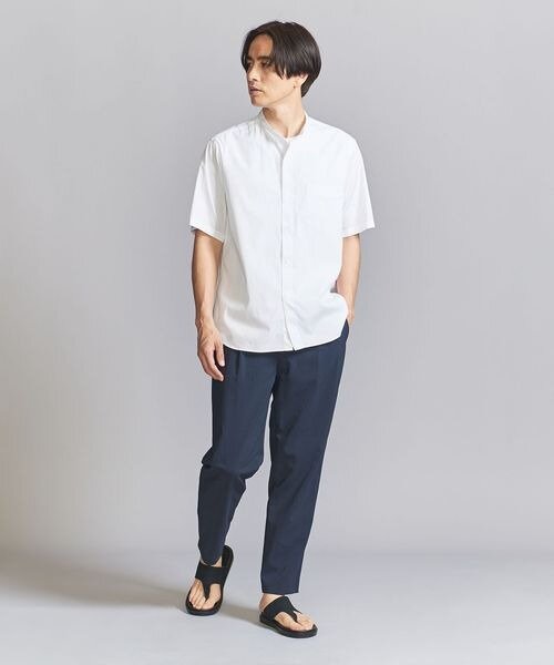 白いシャツにネイビーのパンツを履いた男性