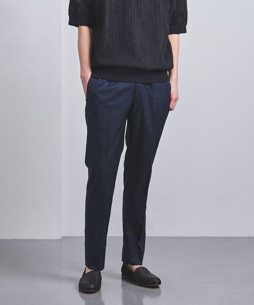 ネイビーのテーパードパンツをはく男性