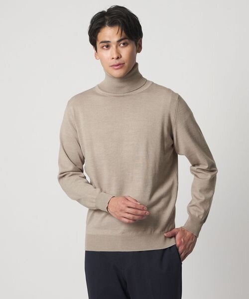 ベージュのタートルネックセーターを着た男性