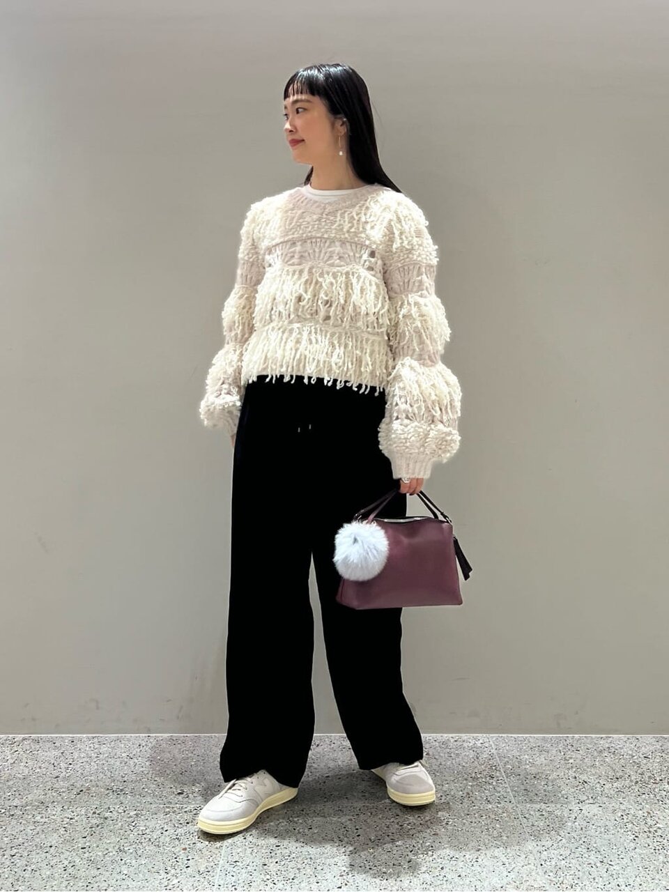 フリンジニットとワイドパンツを着た女性
