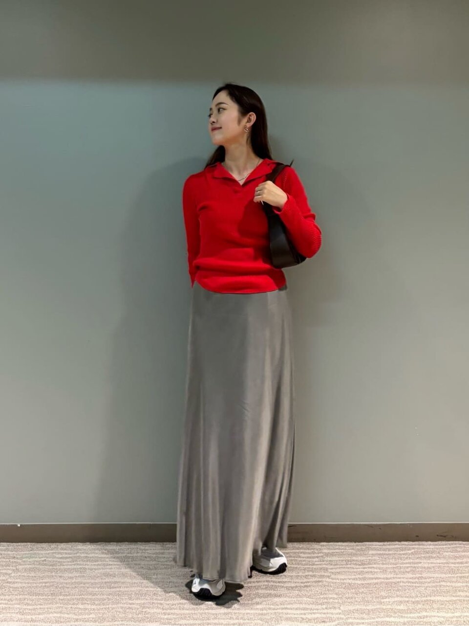 赤いニットとグレーのスカートを着た女性
