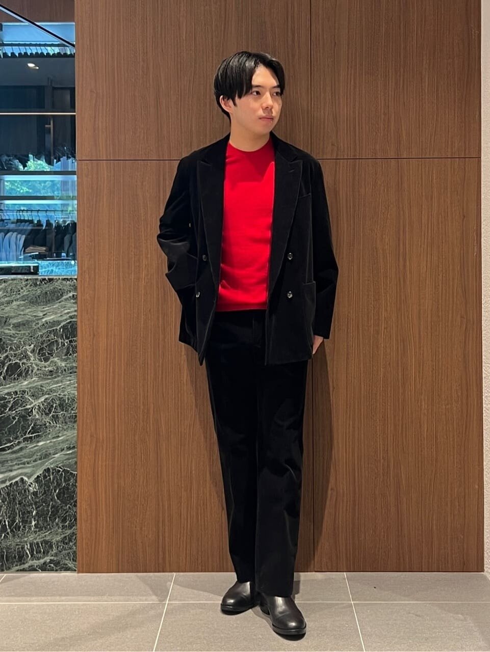 赤いニットに黒のジャケットを着た男性