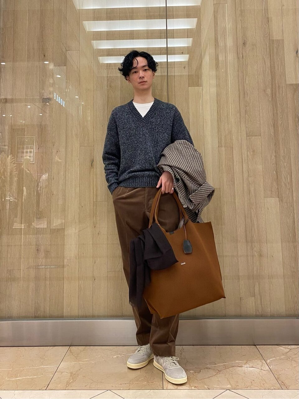 Vネックニットに白のTシャツをあわせた男性