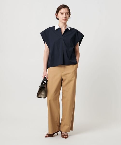 黒のシャツとベージュのチノパンコーデの女性