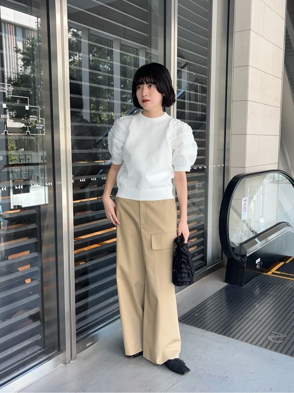 パフスリーブのニットとチノパンコーデの女性