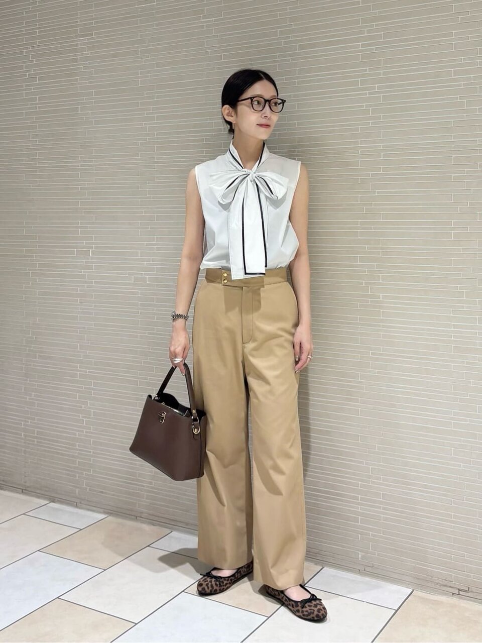 リボンシャツとチノパンコーデの女性