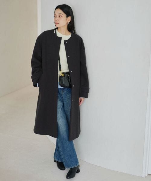 デニムパンツにノーカラーコートをあわせた女性