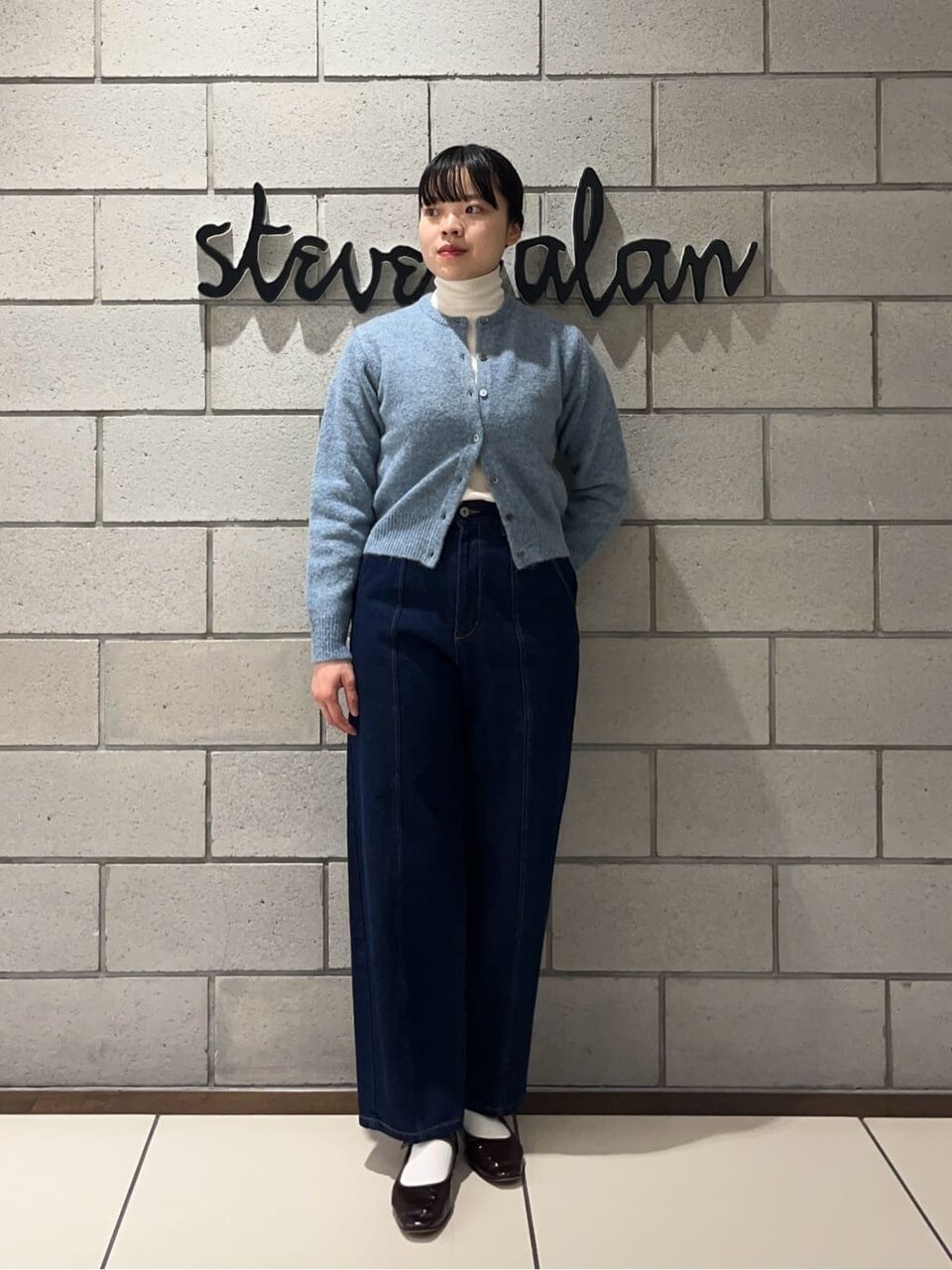 デニムパンツにカーディガンをあわせた女性