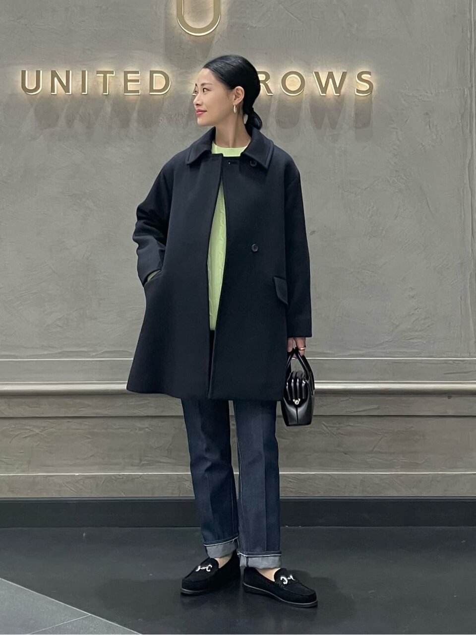 デニムパンツにコートをあわせた女性