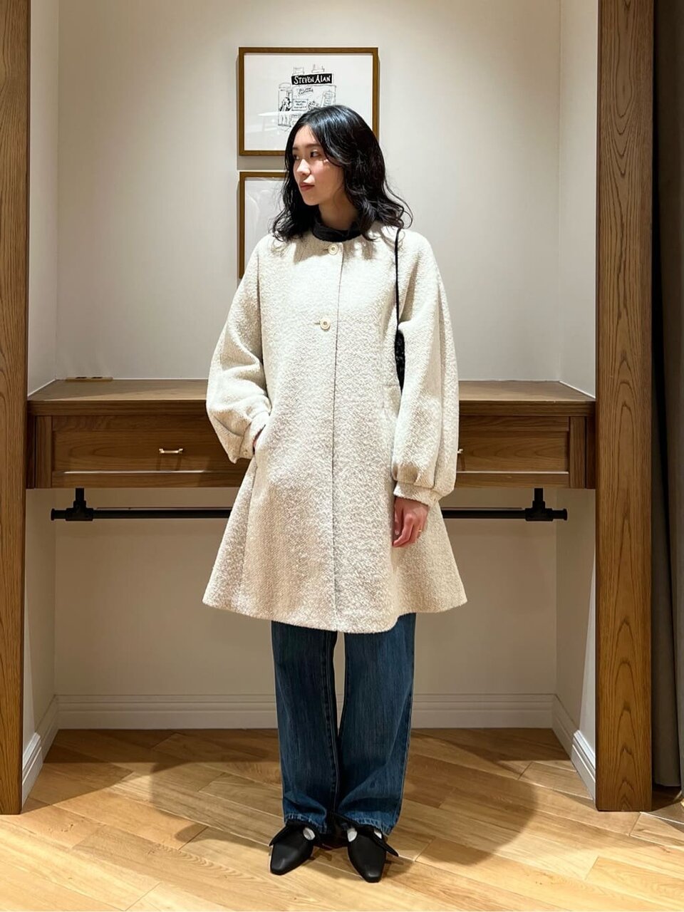 デニムパンツに白のコートをあわせた女性