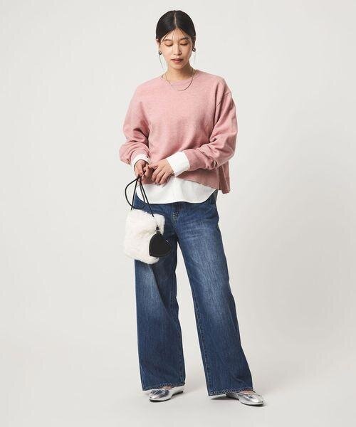 ライトピンクのニットをデニムパンツにあわせた女性