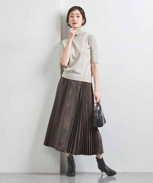プリーツスカートにブーツをあわせた女性