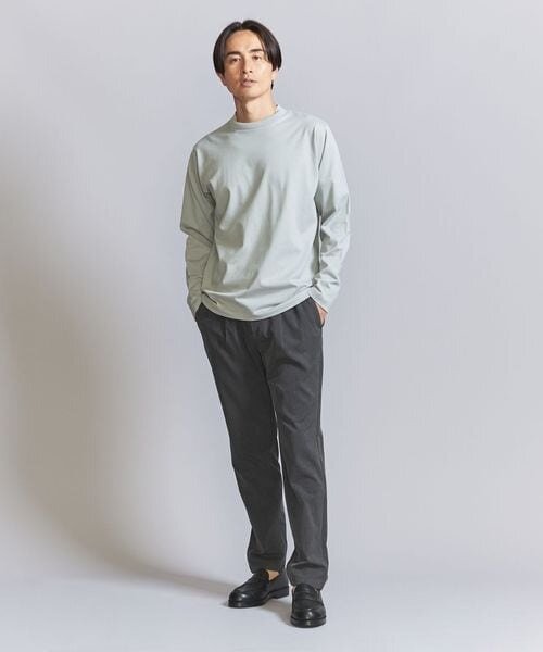 明るい色のトップスとグレーパンツを着た男性