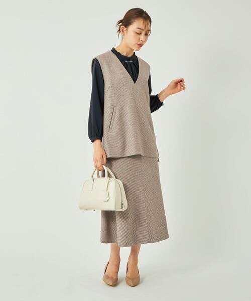 ベージュの上下に黒のインナーを着た女性