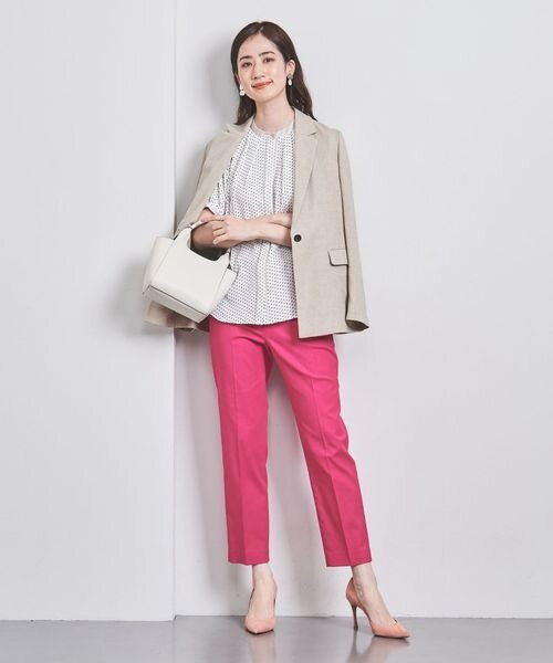 ベージュのジャケットとピンクのパンツコーデの女性