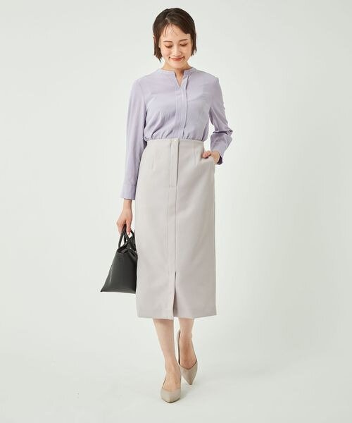 うすいパープルのシャツとベージュのスカートコーデの女性