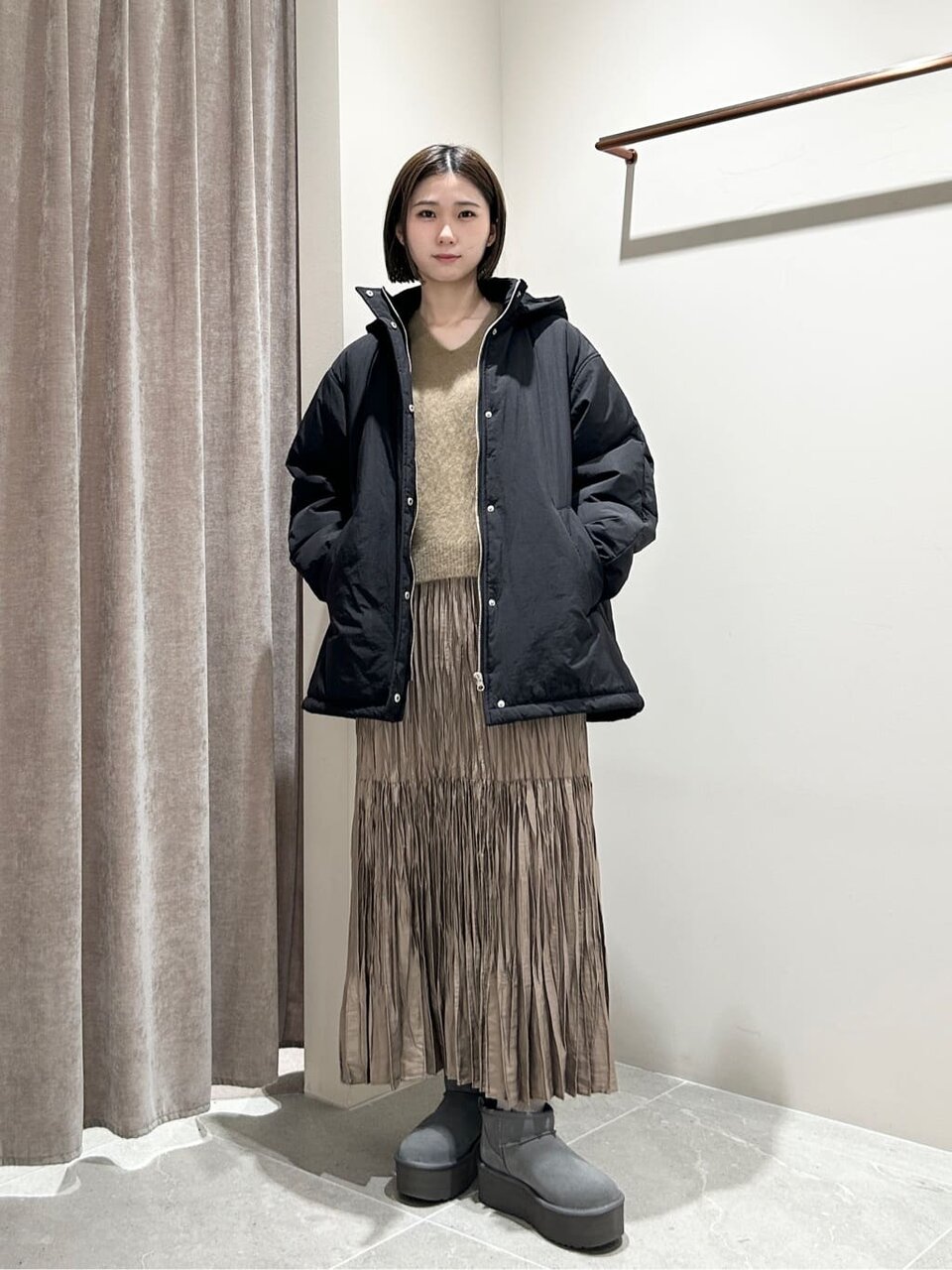 パフブルゾンとプリーツスカートを着た女性