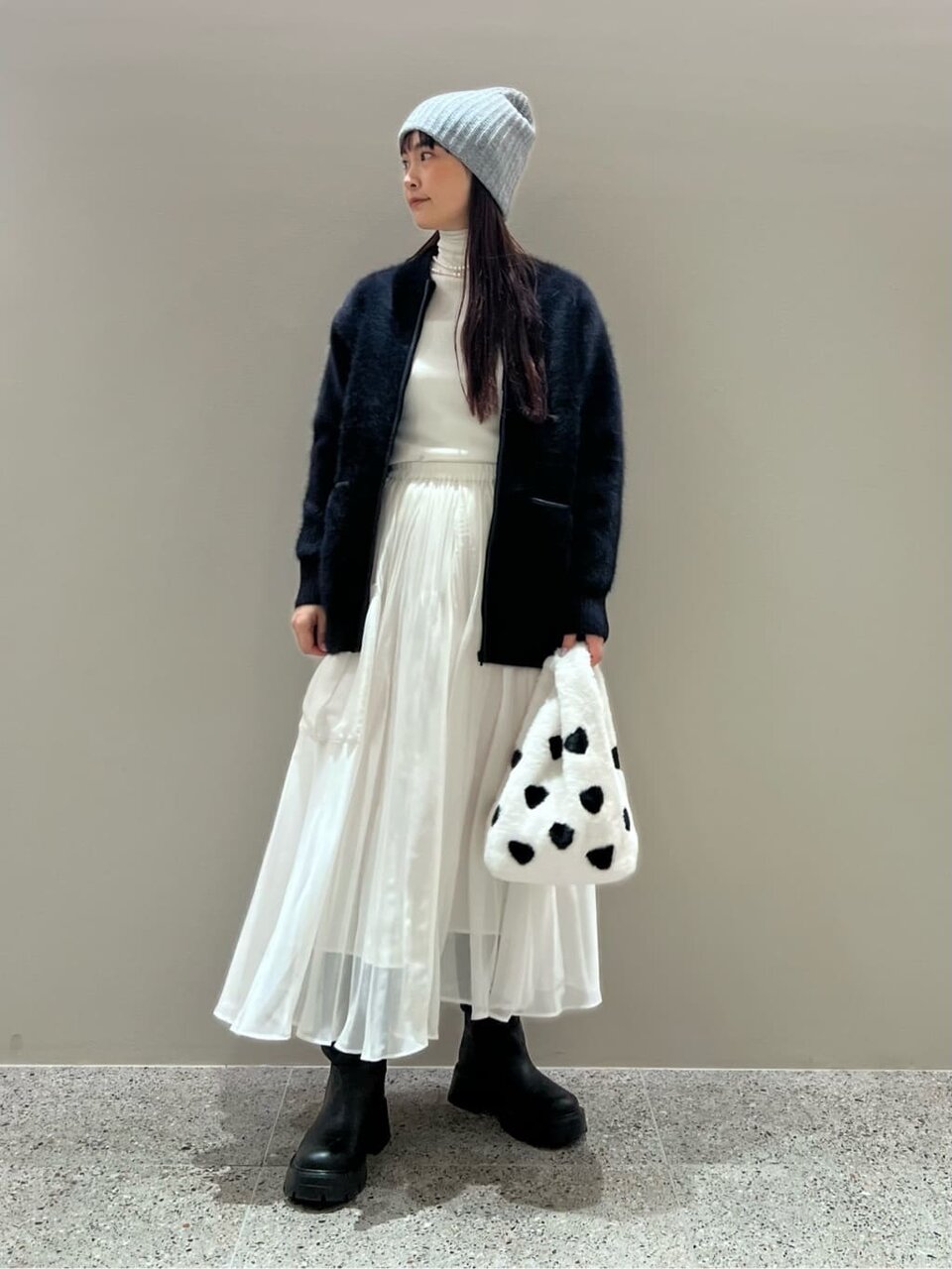 カーディガンとプリーツスカートを着た女性