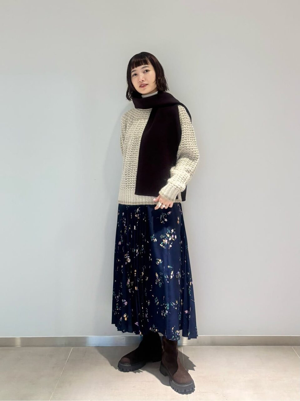 ニットと花柄のプリーツスカートを着た女性